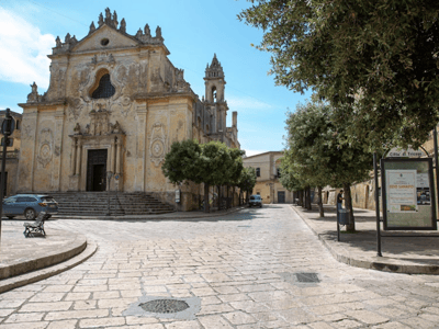 Facade of the Palazzo Gallone, a beautiful baroque architecture, lined with greenery on a cobbled street in Matino, Italy.