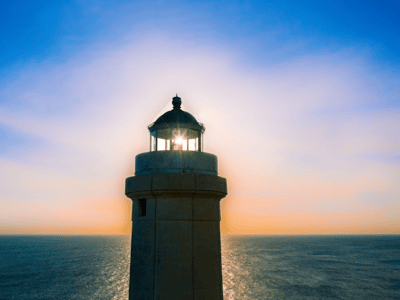 Phare de Punta della Palascia illuminant l'horizon maritime au coucher du soleil, avec des reflets dorés sur l'eau.