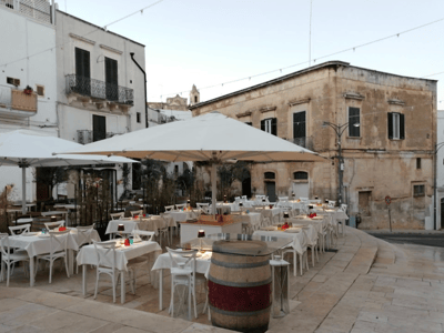 Elegant terrace of a restaurant in C, with white tables under umbrellas, perfect for outdoor dining.