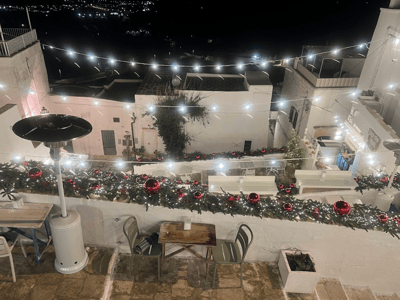 Terrace decorated with fairy lights and red balls, nighttime view of Borgo Antico, festive and warm atmosphere.