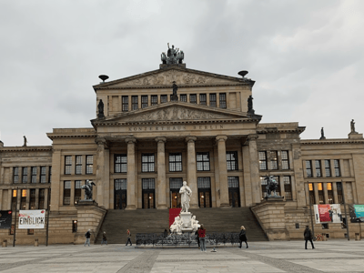 Iconic facade of the Konzerthaus in Berlin, with its central statue and visitors admiring the neoclassical architecture.