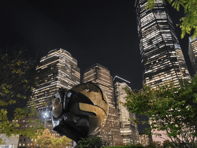 Illuminated modern sculpture, surrounded by shining skyscrapers in Midtown Manhattan, illustrating the night urban architecture.
