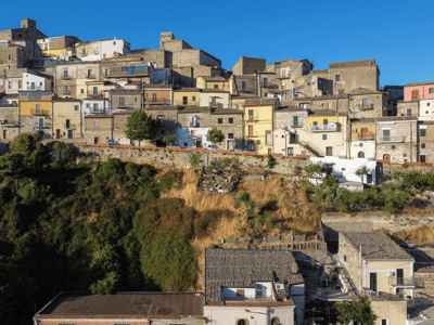Vue panoramique de Sant'Agata di Puglia, avec des maisons colorées sur une colline verdoyante sous un ciel bleu.