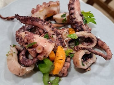 Salade de poulpe assaisonnée, servie avec des herbes fraîches au restaurant Il Capriccio, cuisine méditerranéenne raffinée.