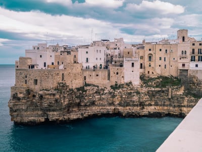 Vue pittoresque de Polignano a Mare avec ses maisons anciennes surplombant la mer turquoise et les falaises escarpées.