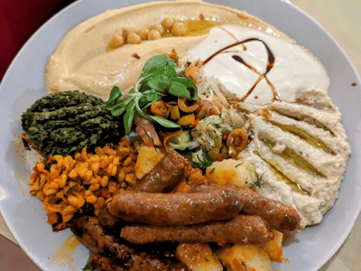 Un plat coloré de mezze avec houmous, viandes grillées, légumes et condiments, représentant la cuisine de Baraka.