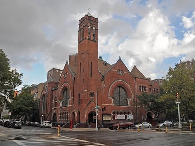 Historic red brick church in Harlem, featuring distinctive architecture and a lively urban environment.