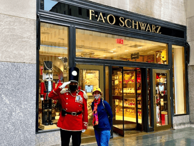 Visitors posing in front of the famous F.A.O. Schwarz store in New York, with a soldier in uniform in the background.