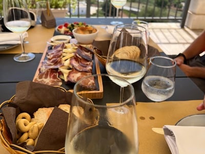 Tasting table at the Pavì restaurant, with wines, charcuterie, and fruits, offering a panoramic view of the countryside.