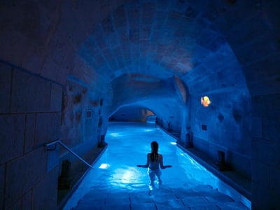 Un couloir de piscine illuminé en bleu, avec une silhouette se déplaçant dans l'eau, à Locanda di San Martino.