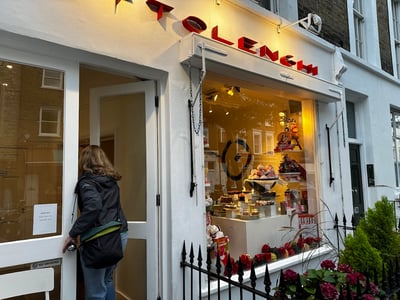 Entrance of the Ottolenghi store in Notting Hill, with a variety of colorful pastries in the display window.