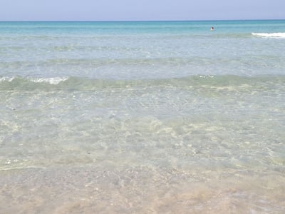 Crystal clear waters at Pescoluse Beach, with gentle waves and a clear sky, perfect for swimming and relaxing.
