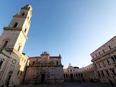 Piazza Duomo de Lecce, montrant la façade baroque de l'église et le clocher majestueux sous un ciel bleu.
