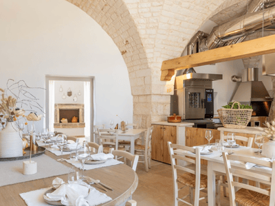 Cozy dining room of Nonno Vittorio, Masseria Valentina, with wooden tables and modern kitchen visible in the background.