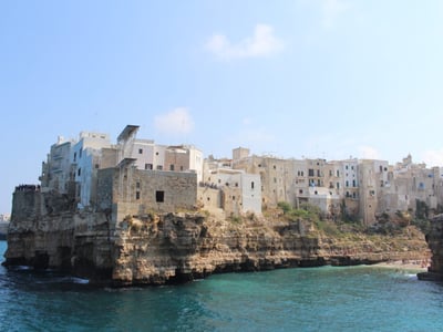 Falaises de Polignano a Mare avec des bâtiments historiques surplombant la mer turquoise. Atmosphère méditerranéenne charmante.