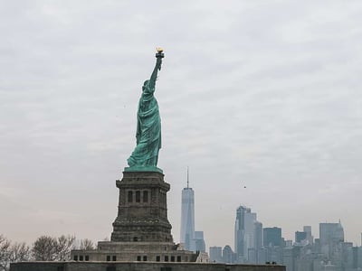 The Statue of Liberty, luminous and majestic, stands with the New York skyline in the background.