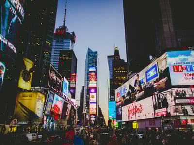 Animations lumineuses et foule à Times Square, symbole vibrant de New York au crépuscule.