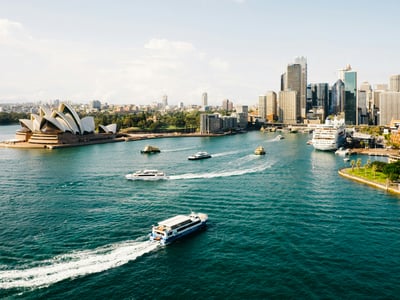 Vue panoramique du port de Sydney, avec l'Opéra et de nombreux ferrys naviguant sur les eaux émeraude.