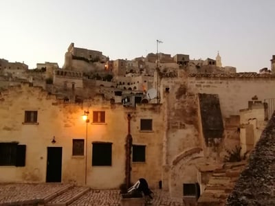 Vue des ruelles pittoresques de Sasso Caveoso, illuminées par des lampadaires au crépuscule, offrant un charme historique unique.