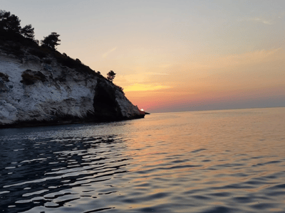 Sunset over Vignanotica Bay, reflecting calming colors on the tranquil water.