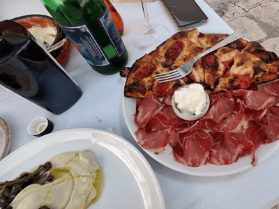 Charcuterie plate and garnished focaccia, accompanied by a beer, at Osteria Luce, showcasing Italian cuisine.