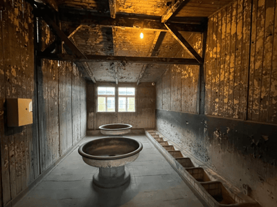 Intérieur délabré d'une salle de Sachsenhausen, avec bassins circulaires et murs abîmés, témoignant du passé sombre du site.