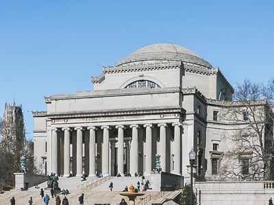 Columbia University Library with majestic columns, students and visitors enjoying the beautiful weather.