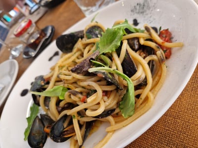 Pâtes aux moules fraîches avec une sauce tomate aromatique, servies chez Spaghetti d’Italia. Parfait pour un repas savoureux.