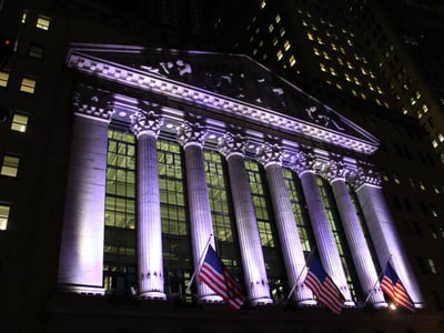 Façade illuminée de la Bourse de New York sur Wall Street, symbole financier emblématique sous un ciel nocturne.