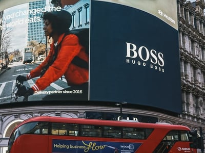 Panneau publicitaire numérique à Piccadilly Circus, montrant une jeune femme à vélo et une annonce pour Hugo Boss.