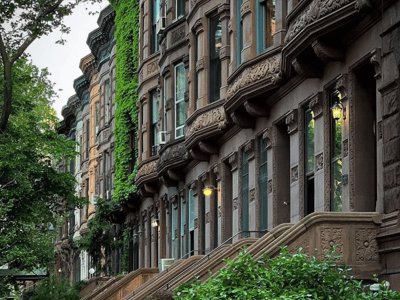Façades de maisons en grès brun sur l'Upper West Side, avec des détails architecturaux et des plantes luxuriantes.