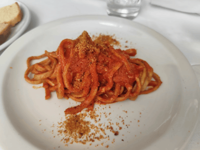 Spaghetti nappé d'une sauce tomate épicée, garnie de miettes croustillantes, servie au restaurant Cibus.