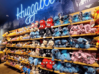 Peluches colorées, y compris Stitch et Spiderman, exposées dans le Disney Store, créant une ambiance ludique et accueillante.