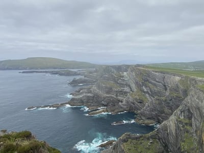 Steep coast of County Kerry, offering breathtaking views of the ocean and lush landscapes under a cloudy sky.