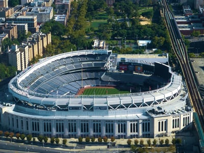 Stade des Yankees à South Bronx, emblème du baseball américain, entouré de verdure et de bâtiments urbains.