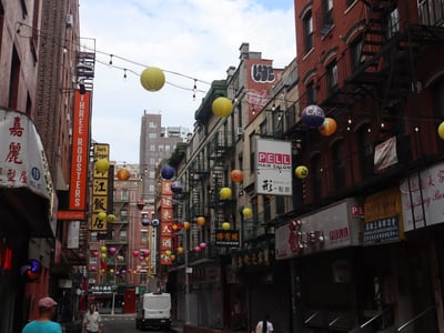 Lively alley in Chinatown, New York, adorned with colorful lanterns and shop signs, illustrating Asian culture.
