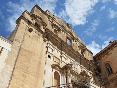Baroque architecture of the Church of San Domenico, highlighted by a light blue sky and clouds.