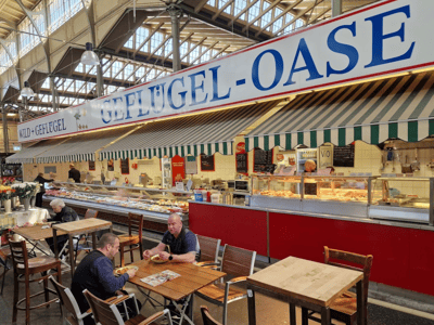 Délicieux plats de volaille servis dans l'Arminiusmarkthalle, avec des clients profitant de l'ambiance conviviale.