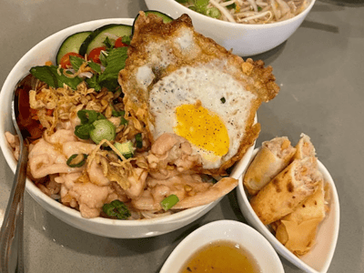 Bol de nouilles vietnamiennes garni de poulet, œuf au plat et rouleaux de printemps, servi avec une sauce douce au Plum Vietnamese Restaurant.