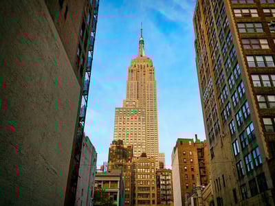 The famous Empire State Building rises majestically under a blue sky in New York, symbolizing American architecture.
