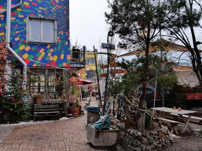 Une ruelle colorée à Holtzmarkt 25, avec des murs peints, des plantes et une atmosphère créative, idéale pour les artistes.