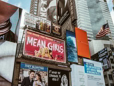 Vibrantes panneaux publicitaires à Times Square, mettant en avant des productions théâtrales comme "Mean Girls" et "Waitress".