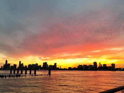 Spectacular sunset on the Manhattan skyline seen from the Pier 57 Rooftop Park, with reflections on the water.