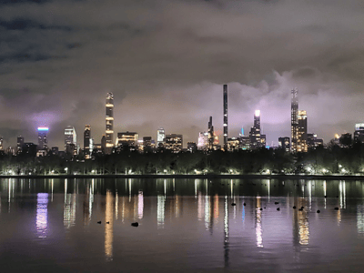 Night view of the New York skyline from the Jacqueline Kennedy-Onassis Reservoir, illuminated by urban lights.