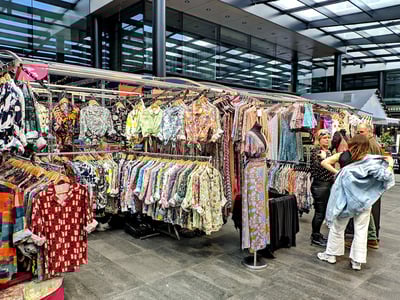 Des vêtements colorés exposés à Spitalfields Market, animant l'atmosphère du marché avec des styles variés et tendance.