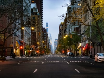 A tranquil view of the Upper East Side, with buildings lining a deserted street and red traffic lights.