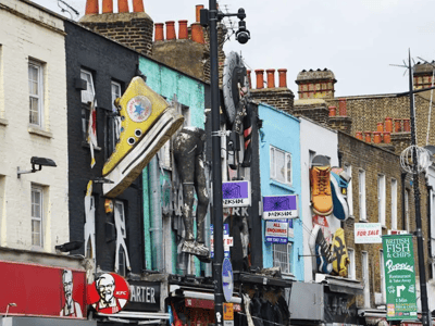 Colorful buildings at Camden Market with original signs, including large shoes and a lively atmosphere.