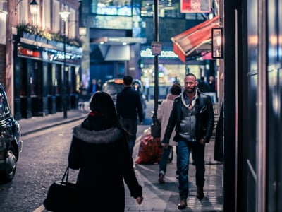 Rues animées de Soho la nuit, avec des passants et des lumières vives des restaurants en arrière-plan.