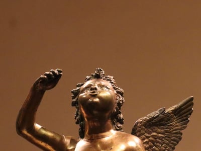 Bronze sculpture of a cherub at the entrance of the Metropolitan Museum of Arts, symbolizing love and beauty.