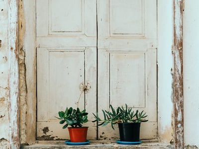 Old window in Grottaglie with plant pots, highlighting the rustic charm of the region.